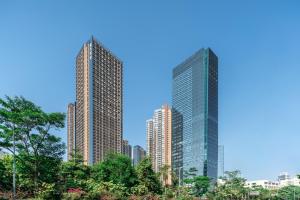 two tall skyscrapers in a city with trees at WESU Weisu Executive Apartment Shenzhen Shenda Metro Store in Shenzhen