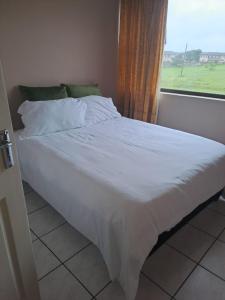 a bedroom with a white bed with a window at 3The Olive Complex Richards Bay 3900 in Richards Bay