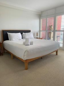 um quarto com uma cama grande com lençóis brancos e almofadas em Northpoint Apartments em Port Macquarie