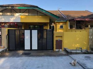 a cat sitting in front of a yellow house at irdahusna homestay in Rasa