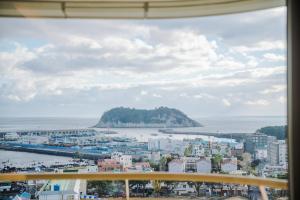 a view of a city and the ocean from a window at Hotel bridge Seogwipo in Seogwipo