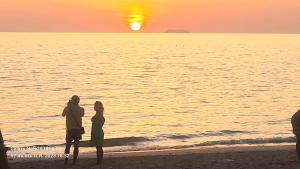 two people standing on the beach watching the sunset at Lanta Amara Resort in Ko Lanta