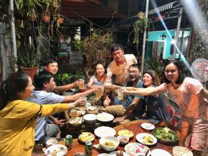 un groupe de personnes assises autour d'une table avec des boissons dans l'établissement Ngoc Lan Homestay 2, 