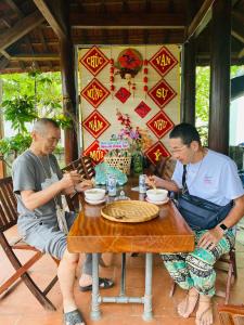 deux hommes assis à une table en train de manger dans l'établissement Ngoc Lan Homestay 2, 