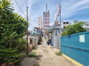 an alley with a blue fence and some buildings at Mon House in Bao Loc