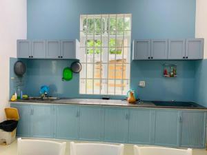 eine blaue Küche mit einem Waschbecken und einem Fenster in der Unterkunft Mon House in Bảo Lộc