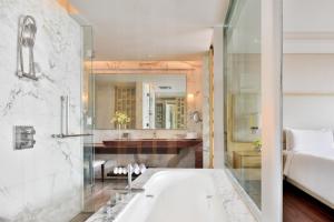 ein Badezimmer mit einer Badewanne, einem Waschbecken und einem Spiegel in der Unterkunft JW Marriott Hotel Chandigarh in Chandīgarh