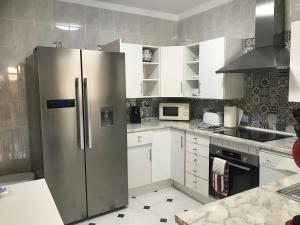 a kitchen with a stainless steel refrigerator and white cabinets at Puerto Pollensa Villa Nevada next to the Beach, private pool in Port de Pollensa