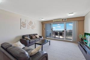 a living room with a couch and a tv at Sandy Cove Apartment The Entrance 29 in The Entrance