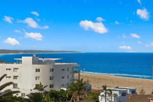 a building on the beach next to the ocean at Sandy Cove Apartment The Entrance 29 in The Entrance