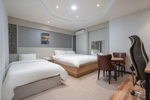 um quarto de hotel com duas camas e uma mesa e cadeiras em BY THS Curve Hotel Ikusan em Iksan