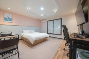 BY THS Curve Hotel Ikusan في Iksan: غرفة نوم بسرير ومكتب وتلفزيون