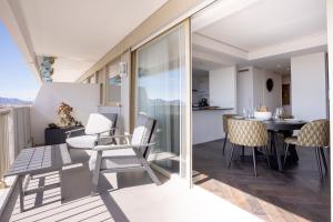 uma varanda com mesa e cadeiras e uma cozinha em Cannes Panorama - Piscine, vue mer, parking, clim em Cannes