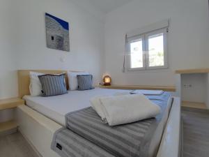 una camera da letto con un grande letto bianco e una finestra di Agnanti Hotel ad Adámas