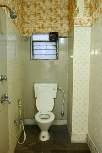 a small bathroom with a toilet and a window at Hotel Komala Vilas in Kolkata