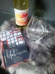 - un verre de vin, un livre et une bouteille de vin dans l'établissement Ferienwohnung Classen Eifel, à Schleiden
