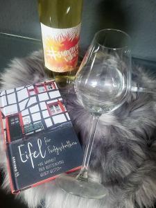 a wine glass and a book and a bottle of wine at Ferienwohnung Classen Eifel in Schleiden +23 photos
