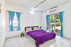 a bedroom with a purple bed and blue curtains at Dev1villa in Lonavala