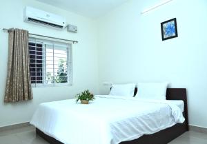 um quarto com uma grande cama branca e uma janela em VINNEST em Tiruchchirappalli