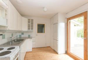 eine weiße Küche mit einer Spüle und einem Kühlschrank in der Unterkunft Cozy Summerhouse by the River in Rovaniemi