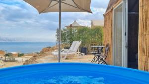 a pool with an umbrella and a view of the ocean at Tenty on the Cliff - Metzoke Dragot in Metsoke Dragot