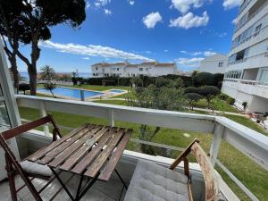 een balkon met een houten bank en 2 stoelen bij Apartamento Los Cisnes in Benalmádena