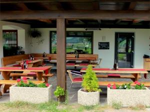 un patio con mesas de madera, bancos y flores en dolomites view apartment en Rasun di Sopra