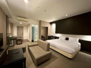 a bedroom with a bed and a couch and a chair at Yasmin Hotel Karawaci in Tangerang