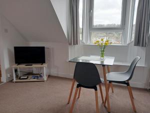 a room with a table and two chairs and a television at Hill View Studio in Hawick