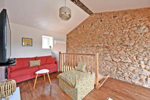 een woonkamer met een rode bank en een stenen muur bij Le Mas des Rouquets - avec piscine et jardin in Anduze