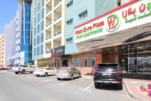 un estacionamiento con autos estacionados frente a un edificio en West Zone Plaza Hotel Apartment (Formerly Winchester Hotel Apts), en Dubái