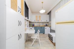 - une cuisine avec des placards blancs et une chaise dans l'établissement Stylish Flat with Modern Design in Antalya, à Antalya