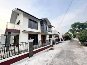 ein Haus mit einem Zaun vor einer Straße in der Unterkunft Villa Munjul Indah - Majalengka in Jatipamor