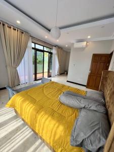 a bedroom with a large bed with a yellow blanket at Villa Munjul Indah - Majalengka in Jatipamor