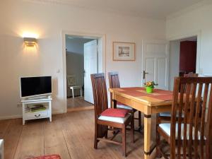 a dining room with a table and chairs and a television at Romantische Ferienwohnung Unter den Linden in Buchholz