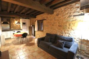 sala de estar con sofá y pared de piedra en Apartamentos Rurales SPA Casa De Los Escudos, en Valverde de la Vera