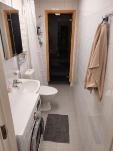 a white bathroom with a sink and a toilet at Top floor flat w. sauna/balcony/free parking in Rovaniemi