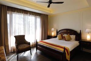 a bedroom with a bed and a chair and a window at A Majestic Luxurious Villa Overlooking The Ganges in Rishīkesh