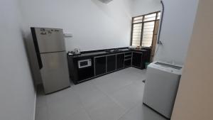 uma pequena cozinha com um frigorífico e um fogão em Homestay Sri Pelangi Segamat em Segamat