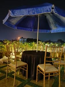 Hotel Mirana , Tinsukia في Tinsukia: طاولة مع كراسي ومظلة زرقاء