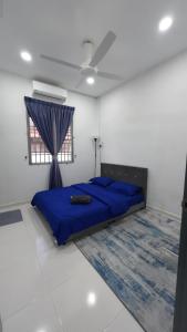 Un dormitorio con una cama azul y una ventana en Homestay Sri Pelangi Segamat en Segamat