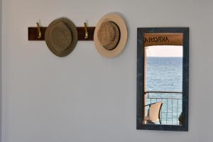 un espejo y un sombrero en una pared junto al océano en Akroyiali - Guesthouse, en Yerolimin