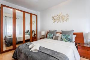 1 dormitorio con 1 cama blanca grande y espejo en Precioso piso moderno: Terraza, A/C, NetFlix, WiFi, en Valencia