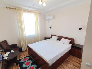 a bedroom with a bed and a table and a window at Caravan Hotel in Khiva