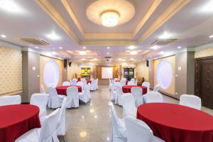 einen Konferenzraum mit roten und weißen Tischen und weißen Stühlen in der Unterkunft โรงแรมมณีสังขะ in Sangkha