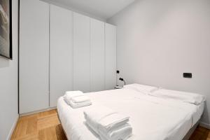 a white bed with three towels on top of it at Ticinese 78 in Milan