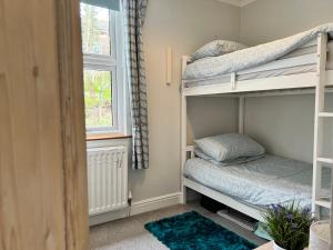 a bedroom with two bunk beds and a window at Cosy Heather Cottage in Ashbourne