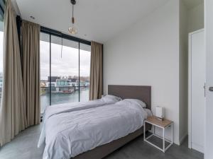 a bedroom with a large bed and a large window at Luxury villa with boathouse on the Veerse Meer in Arnemuiden