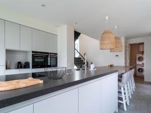 a kitchen with white cabinets and a black counter top at Luxury villa with boathouse on the Veerse Meer in Arnemuiden