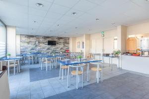 un restaurante con mesas y taburetes en una habitación en Appart'City Confort Brest, en Brest